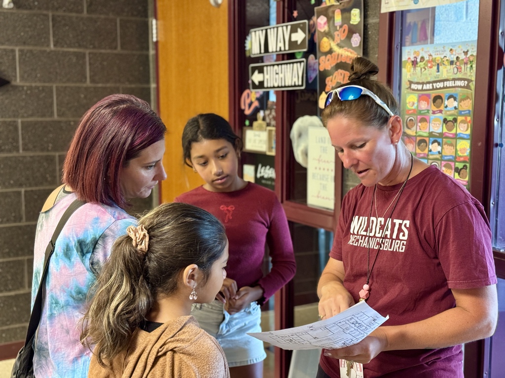 A staff member helps a family find their way through a school building.