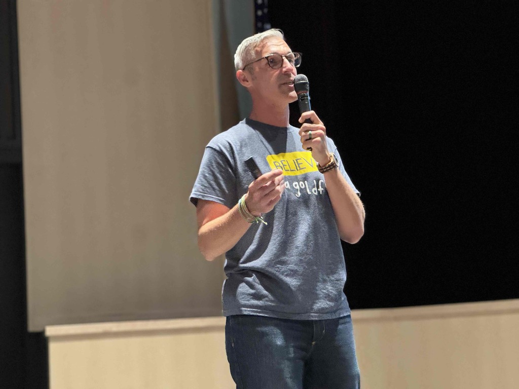 A man speaking with a microphone.