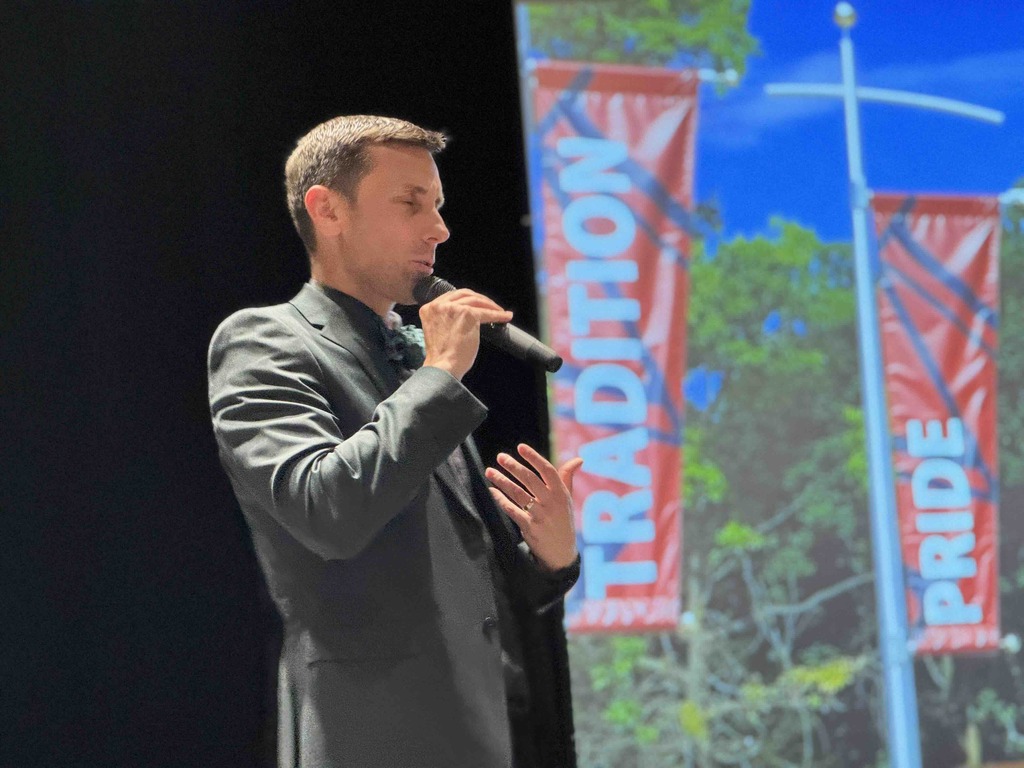 A man with a microphone speaking to a crowd.