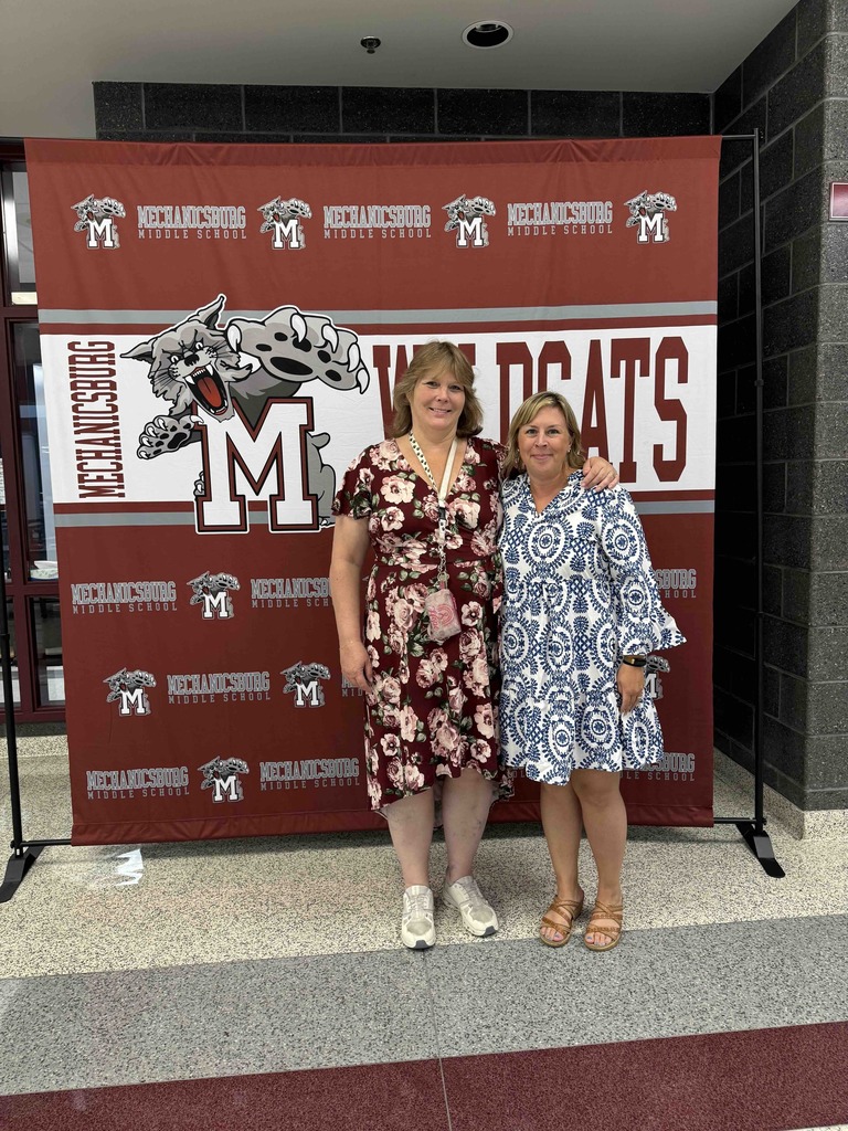 Two ladies standing in front of a Wildcats banner.