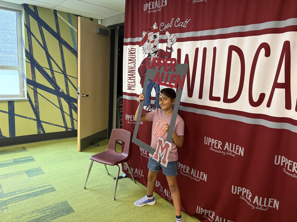 A student standing in front of a banner and holding photo props.