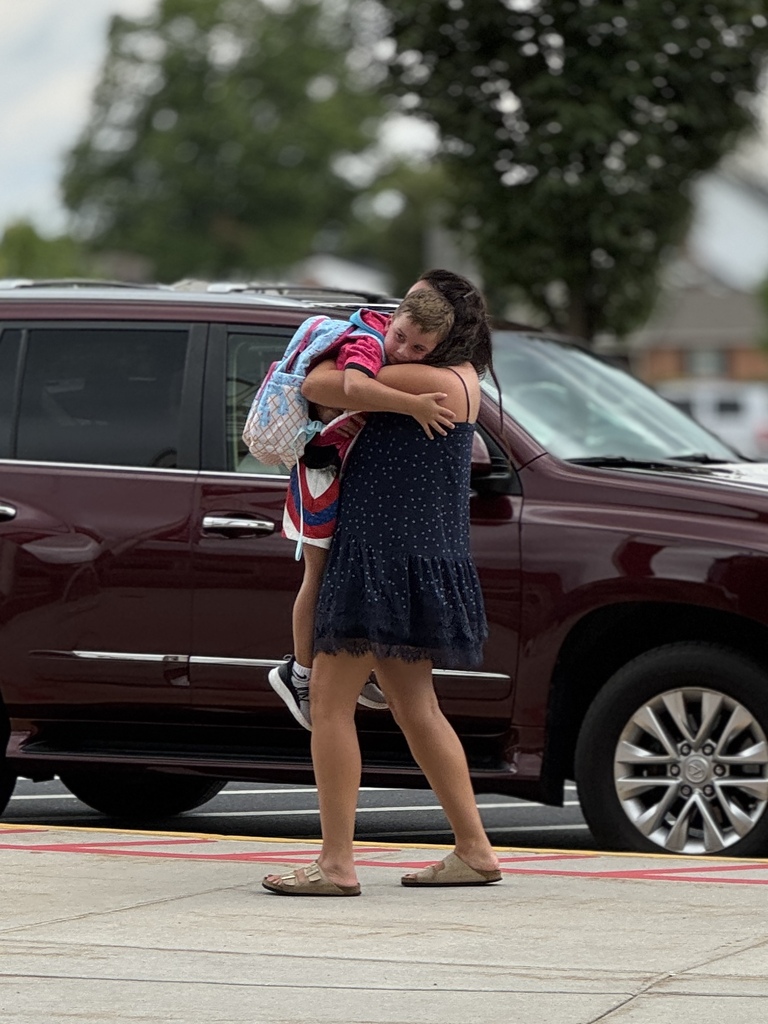 A mom hugs a young student at the end of the school day.