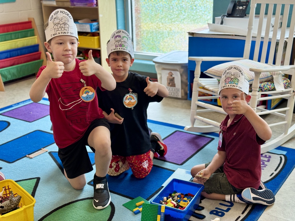 Three boys smile and give thumbs up.