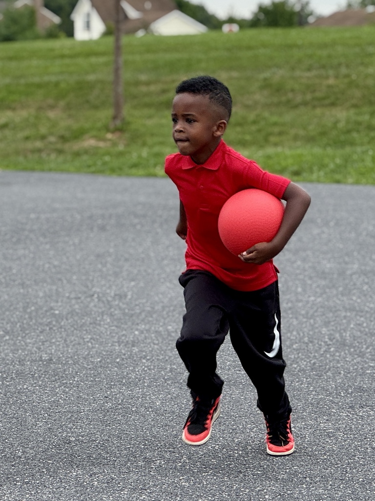 A boy runs with a dodgeball.