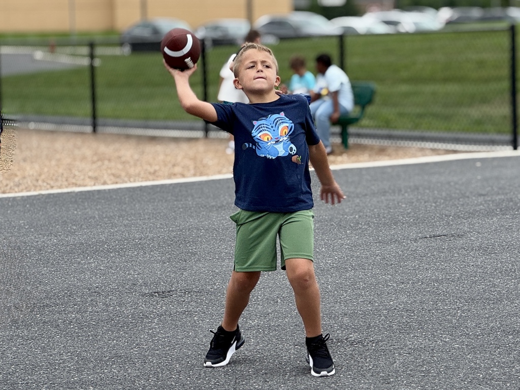 A boy throws a football on a school playground.
