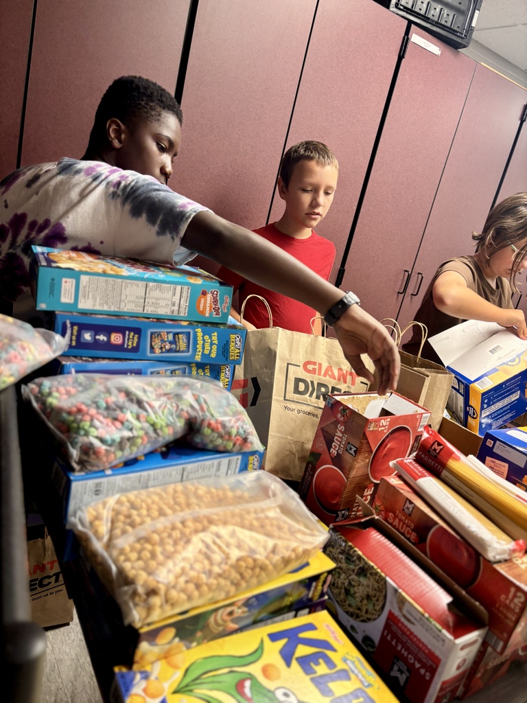 Students stand in front of a table full of food.