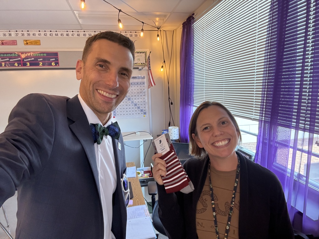 An adult man taking a selfie with a woman who is holding a pair of maroon branded socks.