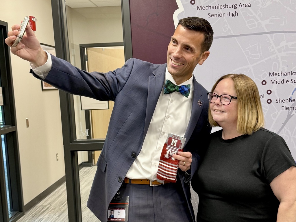 A man taking a selfie of he and a woman he's presenting branded socks to.