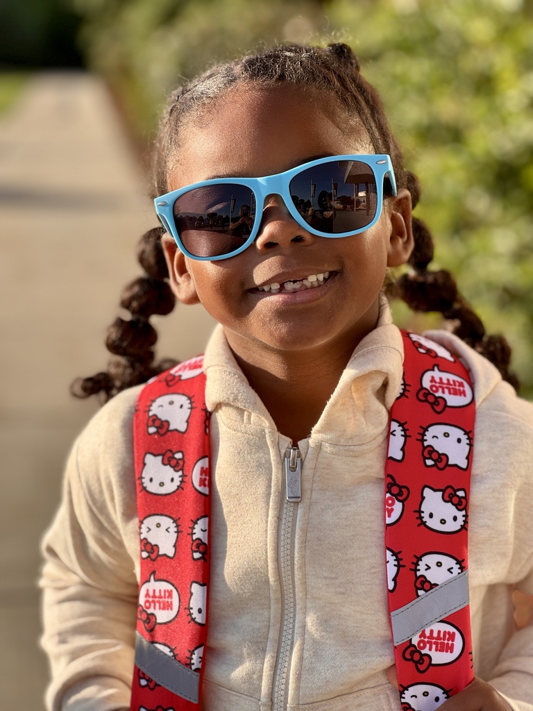 A smiling little girl in blue sunglasses.