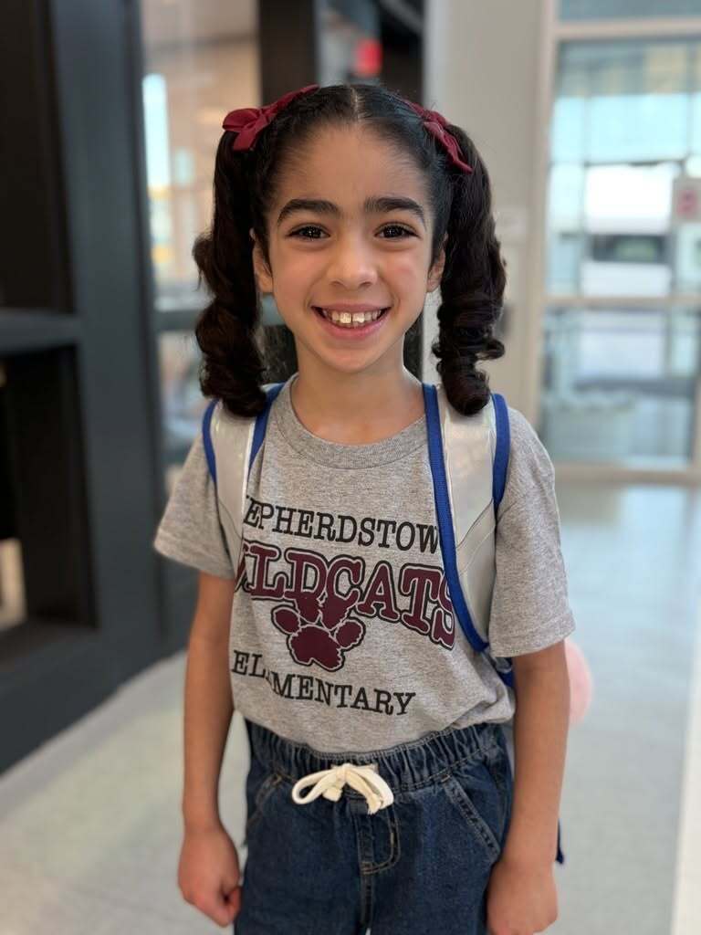 A young girl proudly wears a steel and maroon shirt.