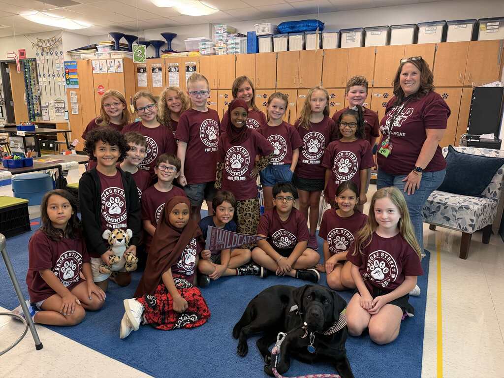A classroom of students showing off their maroon and steel colored shirts.