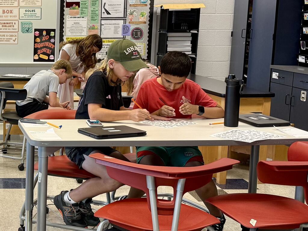 Students work together on math problems in a middle school classroom.