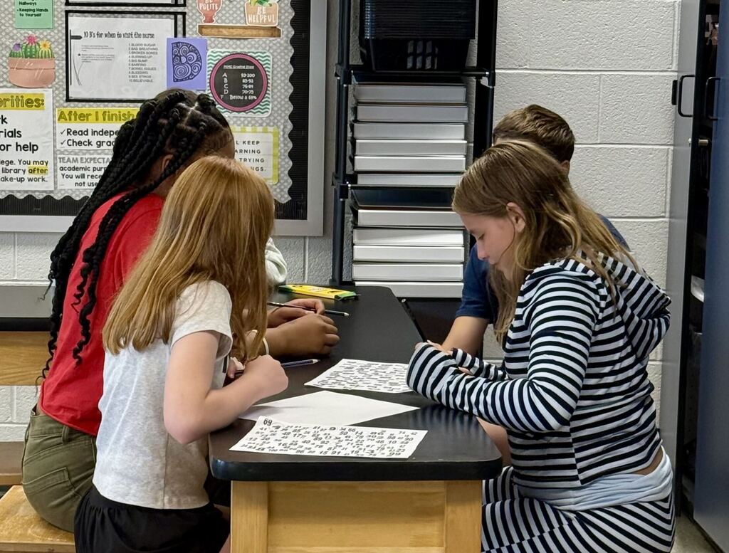 Students work together on math problems in a middle school classroom.