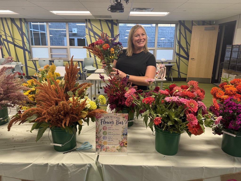 A teacher holds a vase of fresh cut flowers that she just put together.