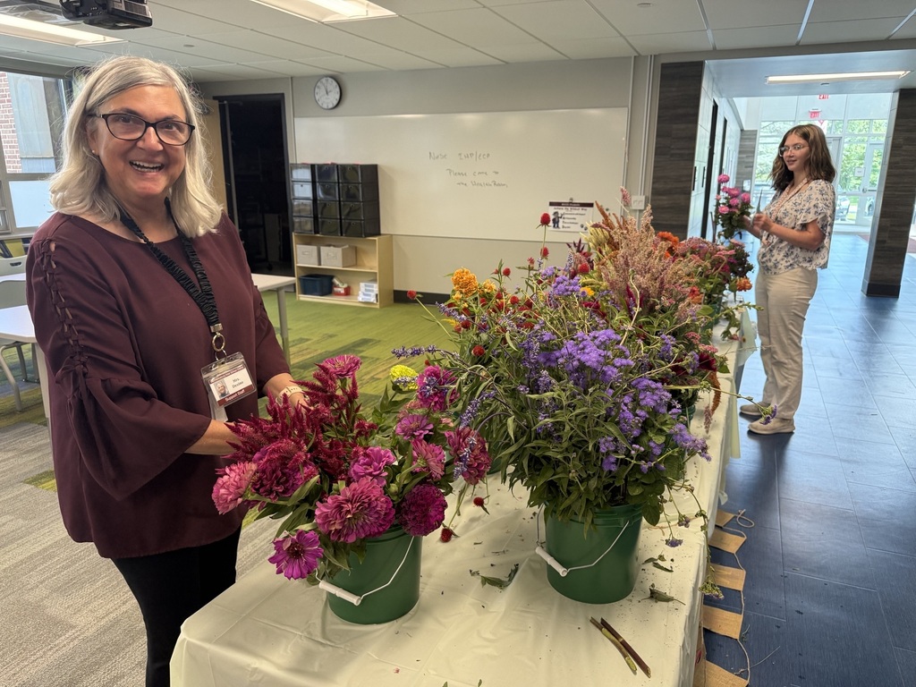 A staff member stands beside a table of fresh cut flowers.