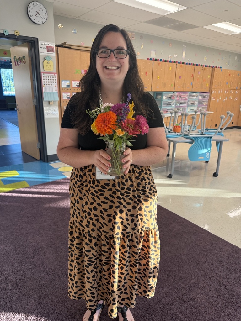 A teacher holds a vase of fresh cut flowers that she just put together.