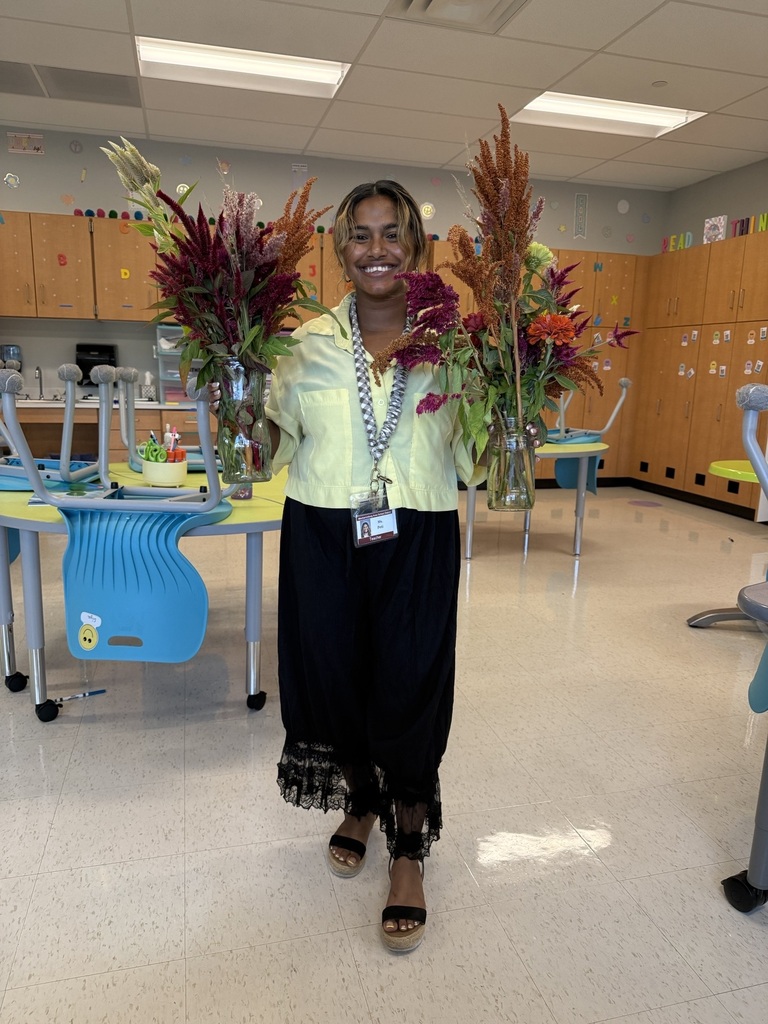A teacher holds two vases of fresh cut flowers.