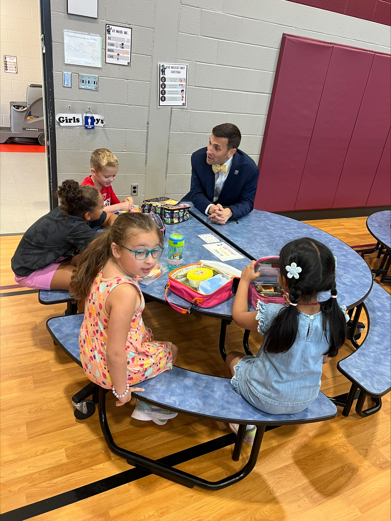 A school superintendent sits with students during lunch.