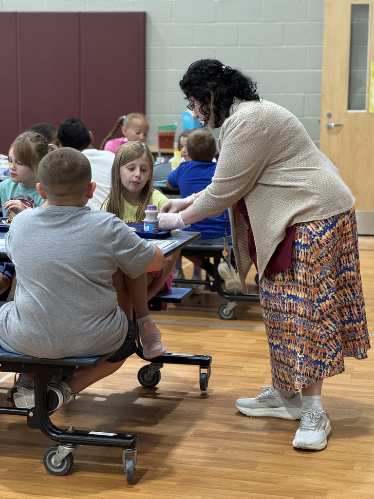 A staff member helps to open a student's food at lunch.
