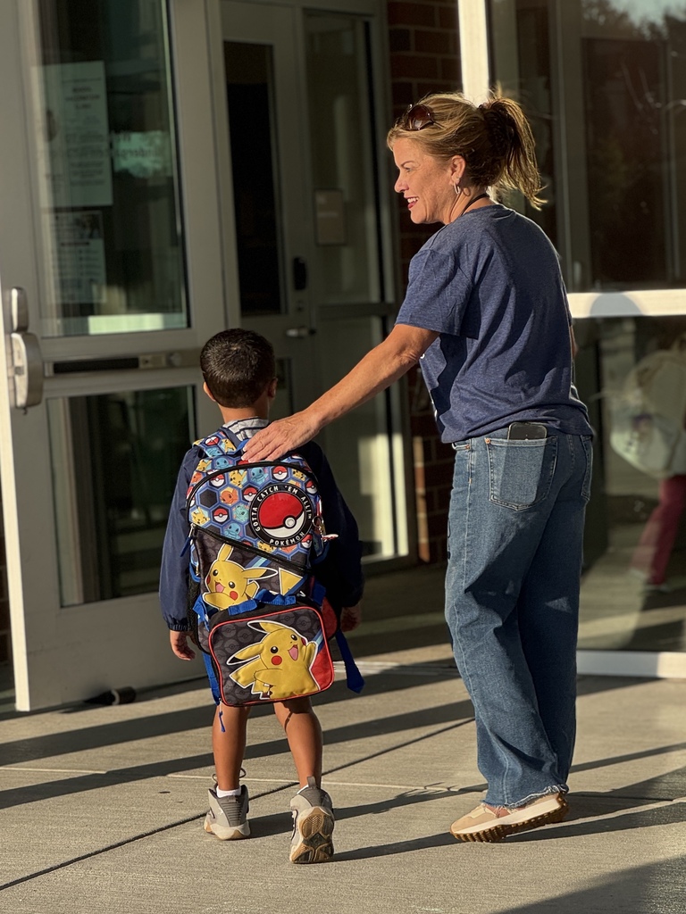 A staff member greets a student at the start of a school day.