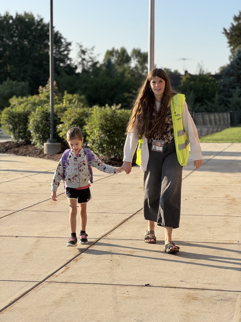 A staff member walks a student into school.