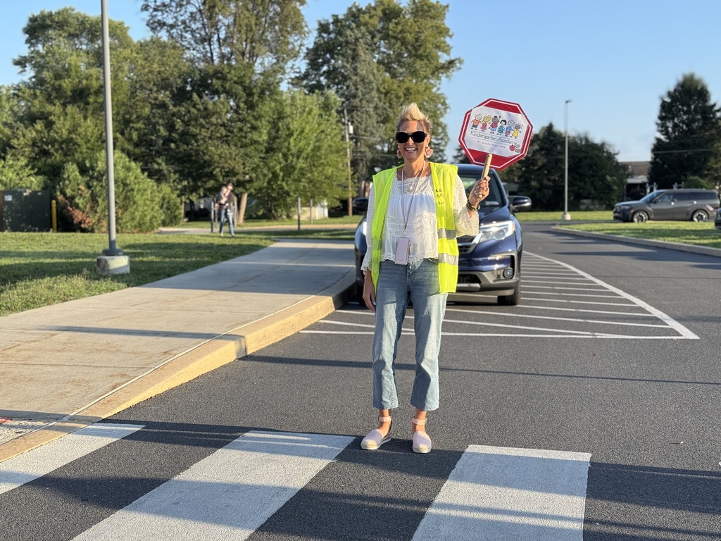 A staff member directs traffic in a bright yellow vest.