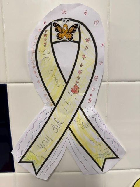 A yellow ribbon colored by classmates that says You Did It, Go Lennon, Good Job!