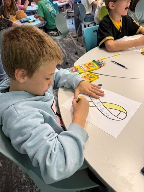 A student colors a yellow ribbon with the words Keep Fighting.