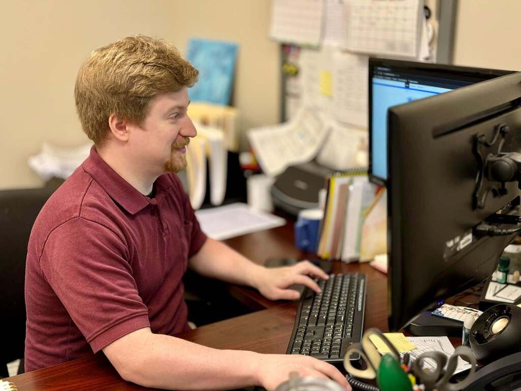 A man sits at a desk to work on a computer.