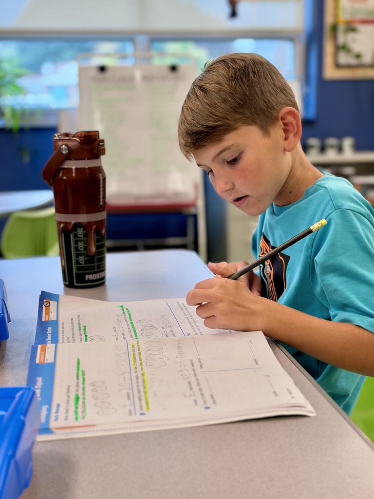A student works on a math assignment at a school desk.