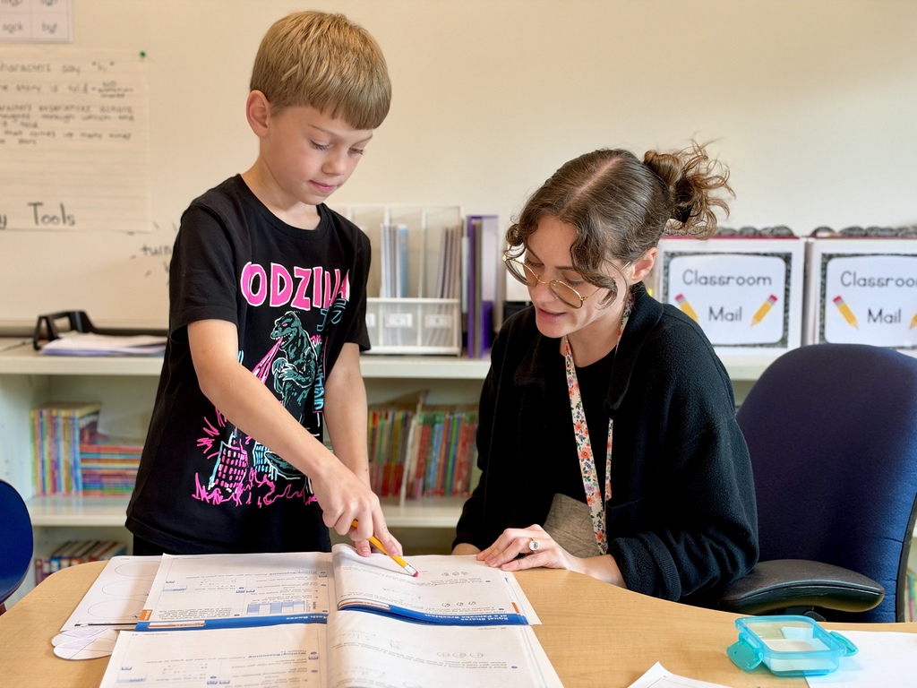 A teacher helps a student with a math workpage.