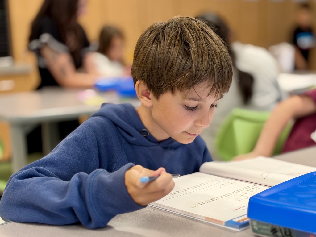 A student works on a math assignment at a school desk.