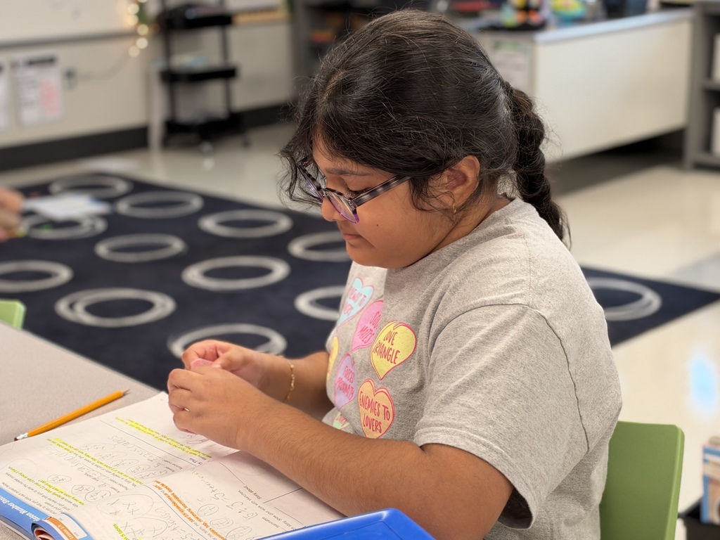 A student works on a math assignment at a school desk.