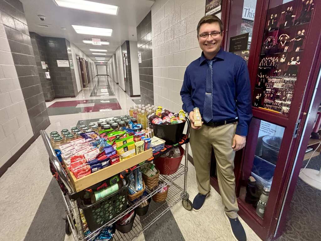 A teacher stands beside a snack cart.