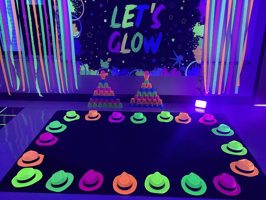 A bunch of glow in the dark hats line a rug in a classroom.