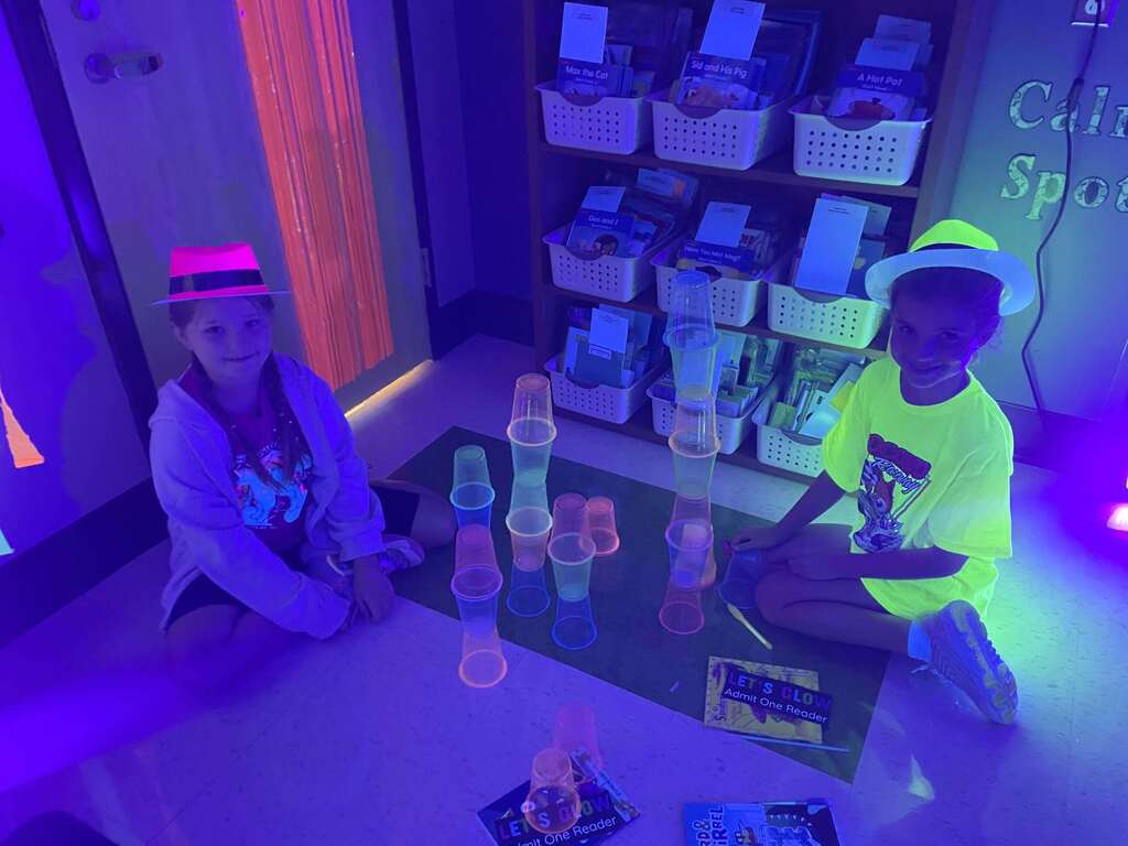 Students play glow in the dark games in a classroom.