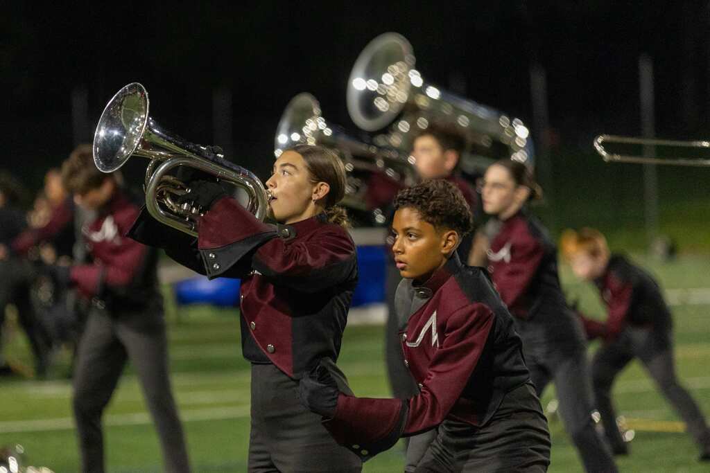 Members of a high school marching band perform during halftime of a football game.