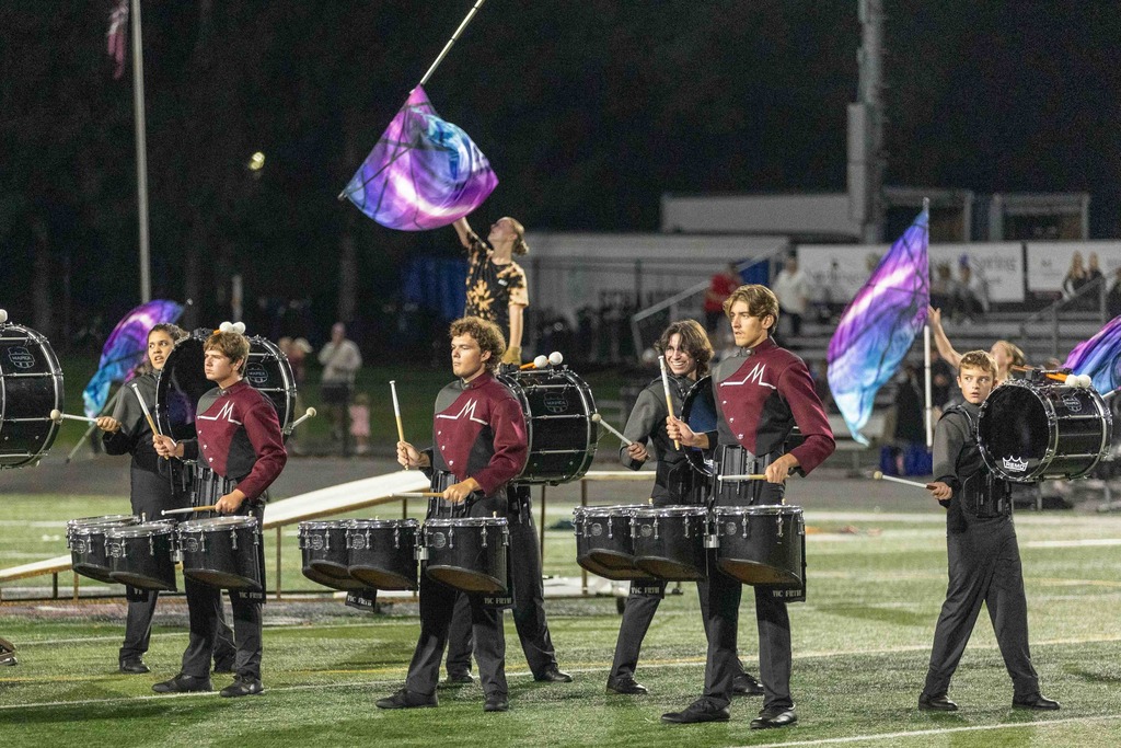 Color guard and percussion line perform during a football game.