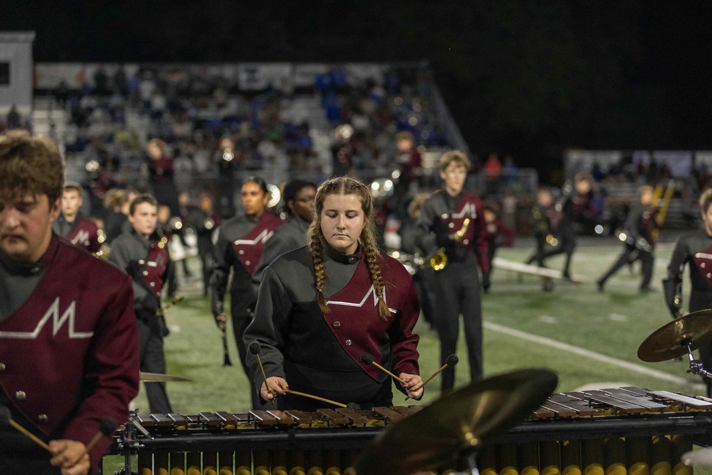 Members of a high school marching band perform during a high school football game.