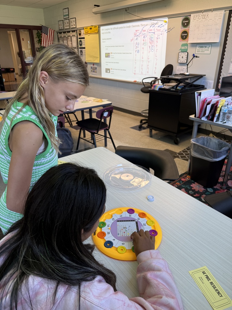 Two students sit at a table and work on a math game.