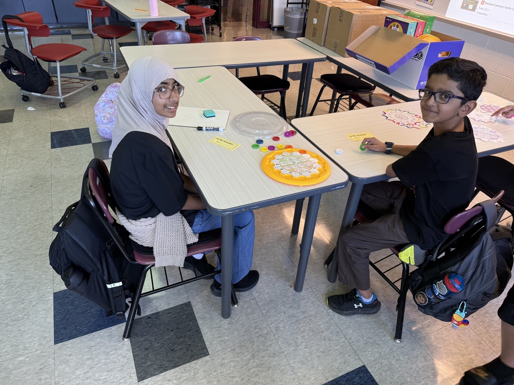 Two students practice math at a table with an interactive game.