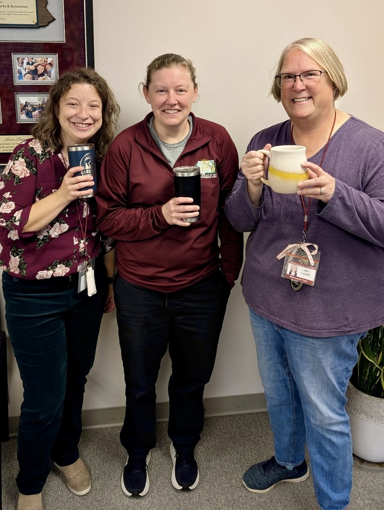 Three staff members hold cups of coffee.