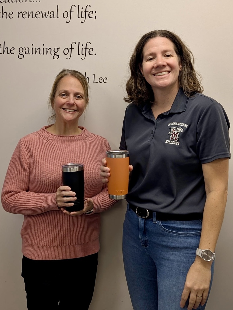 Two staff members hold cups of coffee.