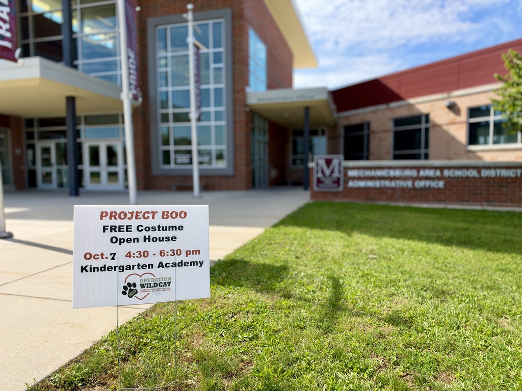 A yard sign displayed in front of a school building.