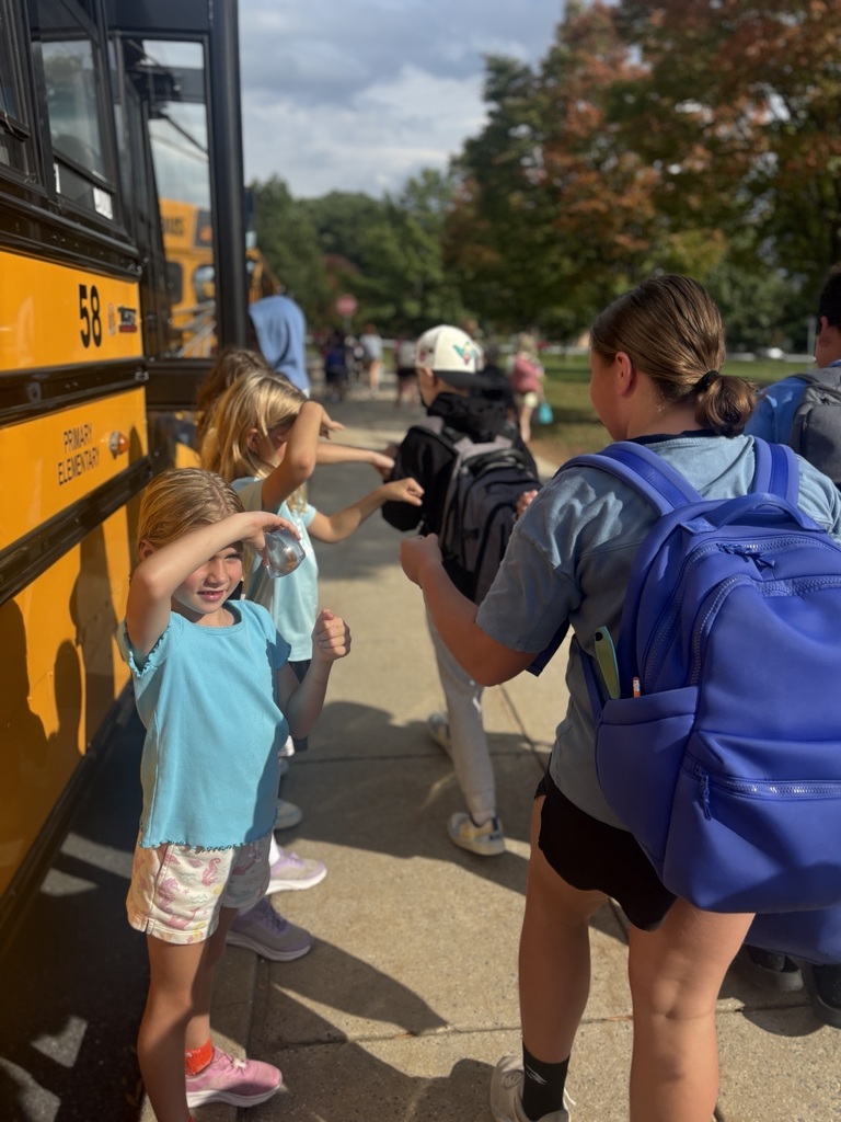Three elementary students give fist bumps to middle school students on their way to the school bus.