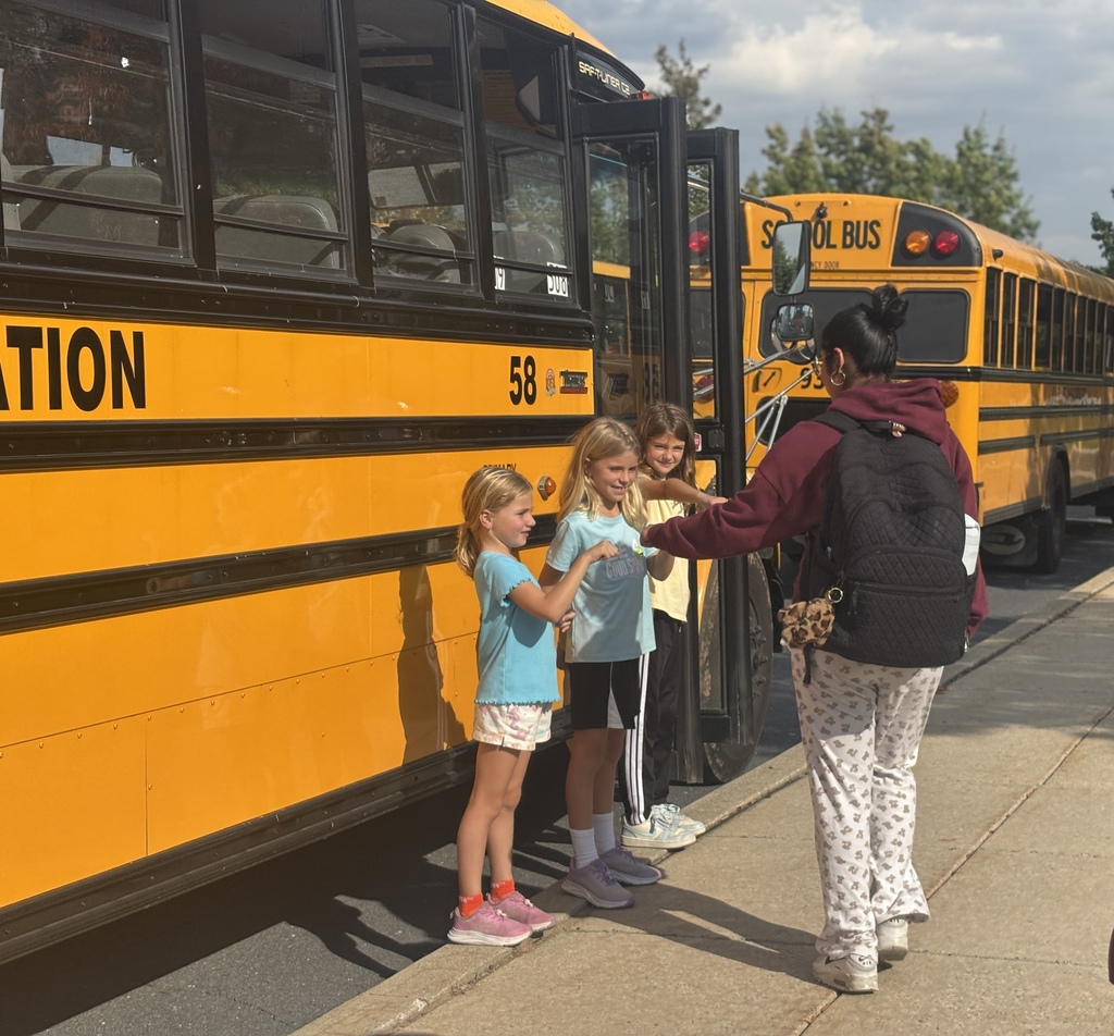 Three elementary students give fist bumps to middle school students on their way to the school bus.