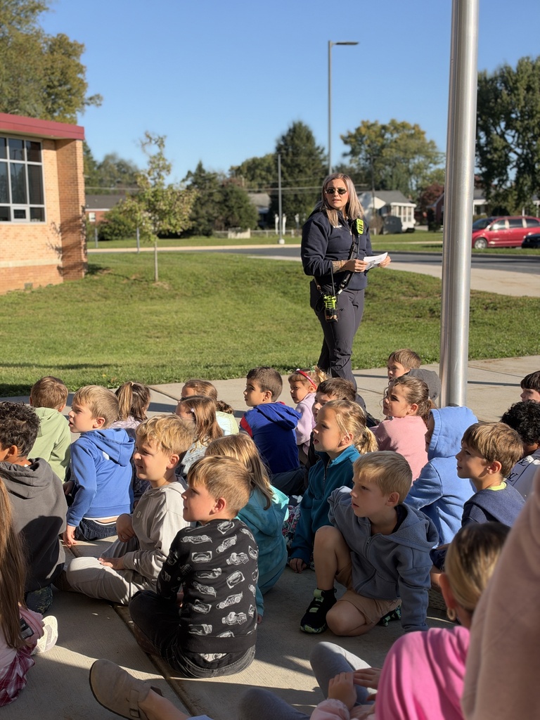 Young students listen to a firefighter speak.