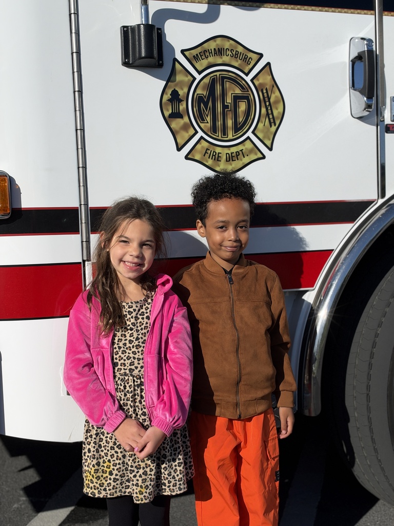 young students pose for a picture in front of a fire truck.