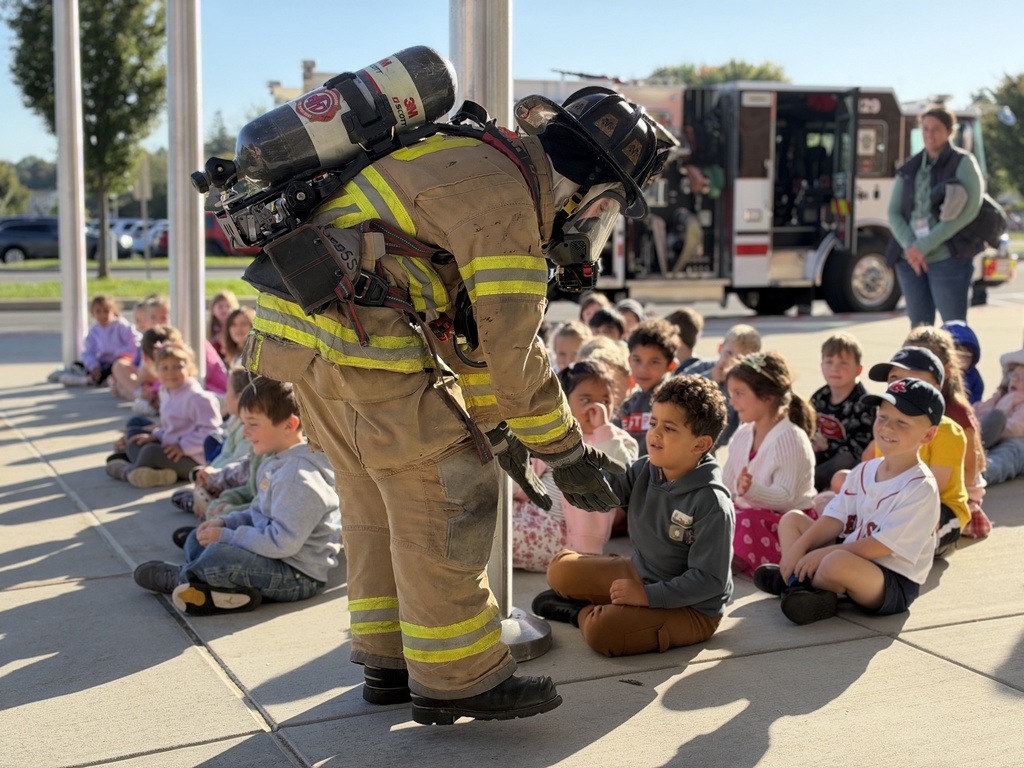 A young student gets a high five from a firefighter.