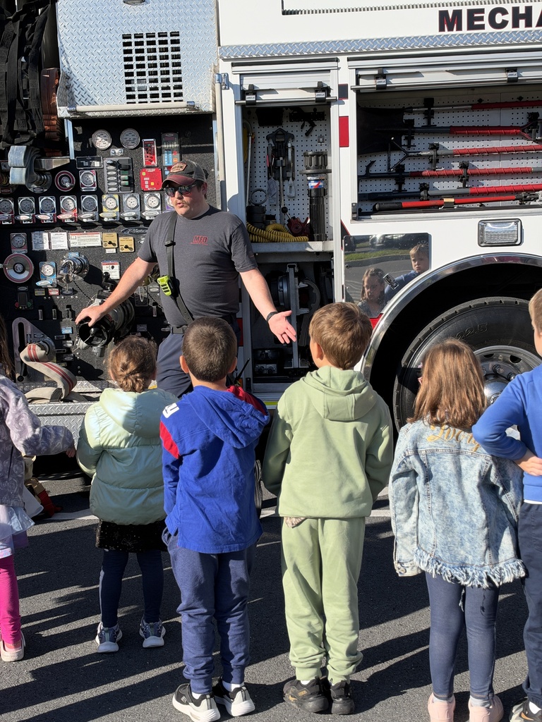 Young students listen to a firefighter speak.